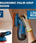 Person using 12V Max Brushless 5 Inch Random Orbit Sander With Ergonomic Palm Grip Dust Collection Variable Speed Soft Start Technology And All Day Comfort For Pro Finishing Workhorse Bare Tool on wood surface.