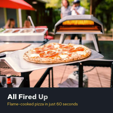 Koda 12 Inch Gas Pizza Oven For Outdoor Cooking With 28 Millibar Regulator And Gas Hose Portable Outdoor Pizza Oven Foundry Black Ready In Minutes Reaches 950 Degrees F So You Can Bake Authentic Stone Baked Pizzas In About 60 Seconds On The Patio with pizza being cooked.