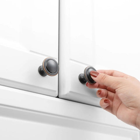 Oil Rubbed Bronze Round Cabinet Knobs One And A Quarter Inch Ten Pack Solid Metal Drawer Pulls For Kitchen Cabinets Dressers Cupboards Bedrooms And Bathrooms Remodel Up Your Space With A Clean Modern Look installed on white cabinet doors with hand opening.