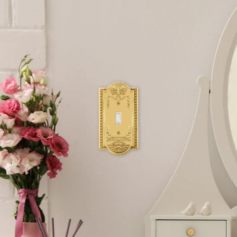 Meadows Light Switch Cover Plate In Greek Revival Style With Decorative Border And Curved Edges shown on wall with flowers