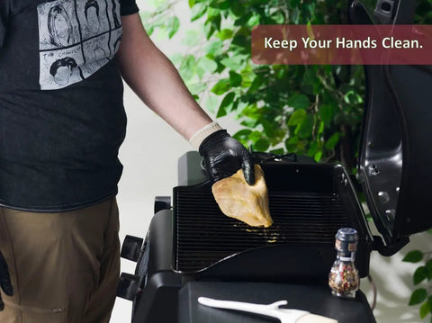 Person grilling chicken using BBQ Glove Set With Four Cotton Liners And One Hundred Black Nitrile Gloves For Grillin And Food Prep.