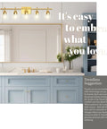 Bathroom with 5 light gold vanity light fixtures over mirror with bell glass shades, blue cabinetry, and decorative elements.
