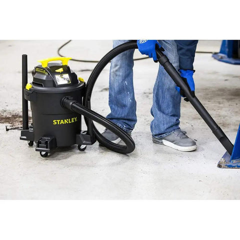 Person using Beast Mode Wet Dry Vacuum With 6 Gallon Tank And 4 HP Power on garage floor, vacuum in action with attachments.