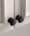 Bulk 25 Pack Black Cabinet Knobs Round Drawer Pulls Zinc Alloy Hardware on white cabinet doors showing sleek modern look.