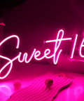 Pink Sweet 16 LED Neon Sign 17 By 7.3 Inches USB Powered Wall Decor glowing in a dark room, centerpiece view