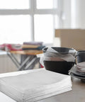 Stack of 100 Pack White EPE Foam Packing Pouches for Moving and Shipping Protection on a table with dishes