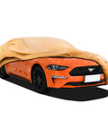 Tough As Nails Heavy Duty Outdoor Car Cover For Ford Mustang 1994 Through 2026 Weatherproof All Weather Waterproof UV Sun Rain Snow Dust Protection Custom Fit Exterior Car Cover partially covering an orange Mustang.