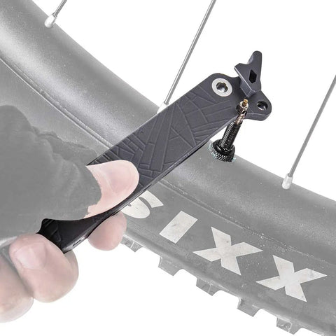 Hand using Power Lever X 5-In-1 Master Link Pliers And Tire Levers With Chain Hook Presta Core Tool on bike tire.