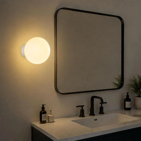 Minimalist Globe Wall Sconce, 1-Light White E27 Round Wall Light Fixture glowing beside a modern bathroom mirror.