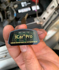 Close-up of hand holding ICar Pro Mini OBD2 Bluetooth Scanner for iOS/Android, showing diagnostic interface label.