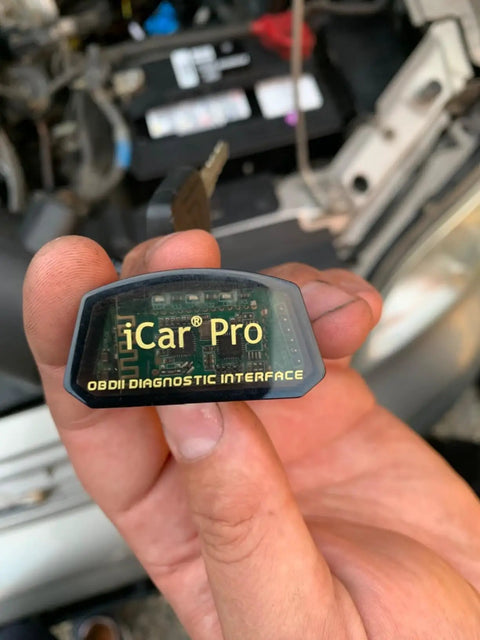 Close-up of hand holding ICar Pro Mini OBD2 Bluetooth Scanner for iOS/Android, showing diagnostic interface label.