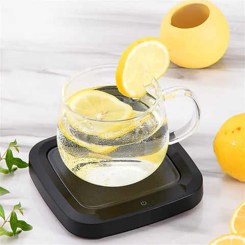 Keep Your Daily Brew Piping Hot With This Smooth Operator Ceramic Coffee Mug Warmer featuring a glass mug with lemon slices on a black base.