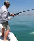 Man using Grab And Go Pocket Telescopic Fishing Rod And Reel Combo on a boat, fishing in clear blue water, pole extended.