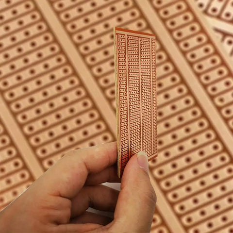 Hand holding 50x100mm Copper Stripboard from 12 Pack For DIY Soldering And Prototyping Projects Single Sided Perfboard