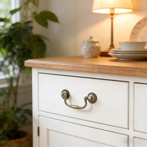 4-Piece Antique Bronze Drop Bail Drawer Pulls With Screws, used on a white cabinet in a cozy room setting.
