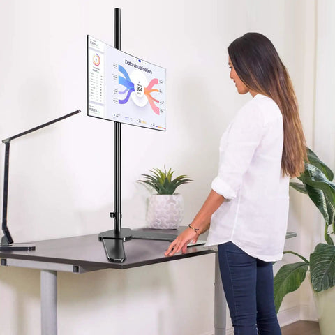 Woman using Tall Floor Monitor Mount With Extra Long 47 Inch Pole For Free Standing Desk Setup Adjustable Single Arm Fits 13 To 27 Inch Screens Up To 22 Lbs Easy Height Tilt And Depth Adjust To Cut Eye Strain at a desk