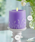 Flameless Moving Flame Goblet Candle With LED Pillar 4 By 4.5 Inch Embossed Floral Print Unscented Real Wax Recessed Edge Timer Remote Ready Lavender Glow on a pedestal