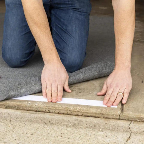 Person applying Indoor Outdoor Carpet Tape One Point Four One Inch By Forty Two Feet White Fiberglass Reinforced Durable Adhesive