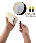Hands inserting batteries into ivory LED candle, 2 AA batteries shown. 12 Pack Flameless Candles With Real Wax Battery Operated LED Pillar Candles Unscented Ivory Color Including Remote Control And 24 Hour Timer Diameter 3 Inches Height 4 Inches Perfect For Cozy Home Vibes Parties Weddings And Events.