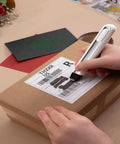 Person using Your Go To 4 In 1 Mini Heat Press Kit With 3 Second Fast Heating to erase label on a cardboard box