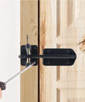 Person using a screwdriver to install a Heavy-Duty Silicone Automatic Gate Latch 7.4 Inch on a wooden door.