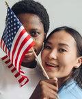 Two people holding a handheld flag from the 12 Pack 8x12 Inch American Flags on Sticks for Outdoor Use with Grounded Multi Purpose Flagpole Handheld Flags
