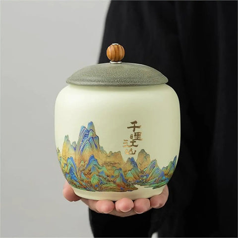 Top Shelf Ceramic Tea Tin With Woven Rattan Travel Case, Stunning Mountain Landscape Design, Go To Stash Jar For Loose Leaf Tea Or Specialty Coffee Beans In Slate Blue, held in hand.