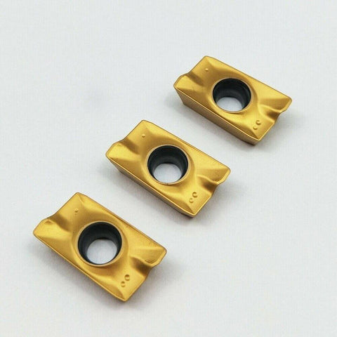 Close-up of three carbide inserts for CNC milling and turning tools APMT1604PDER, multilayer coated for hard steel machining.