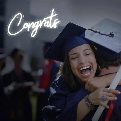 White Congrats Neon Sign Dimmable LED Wall Art For Graduation Party And Wedding Backdrop glowing beside graduates hugging