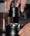 Handheld black Straight Fire Dual Bearing Espresso Distributor And Tamper Combo being placed on espresso machine's portafilter.