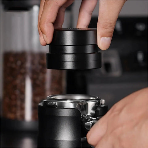 Handheld black Straight Fire Dual Bearing Espresso Distributor And Tamper Combo being placed on espresso machine's portafilter.