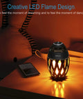 LED Flame Outdoor Table Lamp With Bluetooth Speaker on table, emitting warm light in dark room setting.