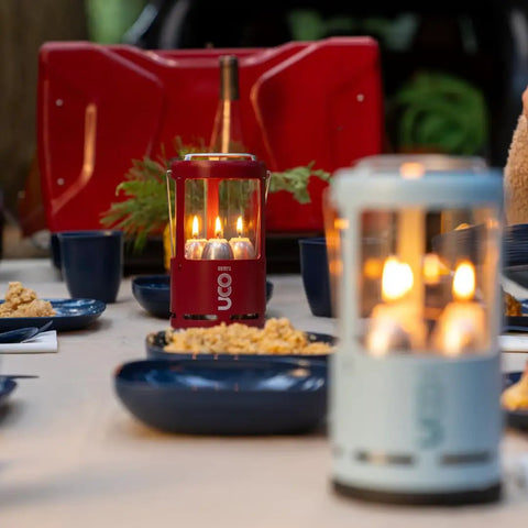 Red Candle Lantern For Camping And Emergencies on picnic table with food, showing aluminum body and glass chimney.