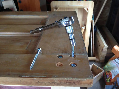 Rock Solid Stainless Steel Lag Screws And Bolts 20 Pack 3/8 Inch By 2-1/2 Inch Hex Head Fasteners in use with a socket wrench on wood.