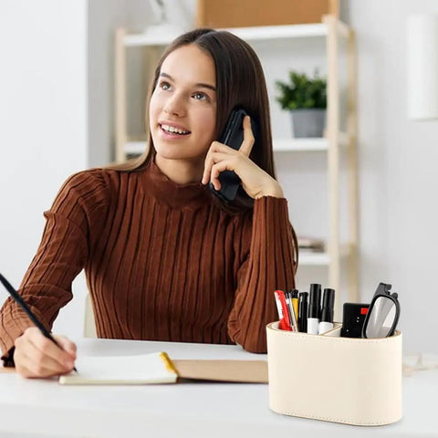 PU Leather Desk Organizer Caddy With Two Compartments Remote Control Holder Pencil Cup on a desk beside a person writing