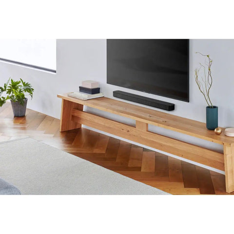 Compact 2 Channel Soundbar With Bass Reflex Built In Tweeter Bluetooth Easy Setup Slim Design For Small Rooms And Home Office Clear Theater Like Audio In Black on wooden media stand under wall-mounted TV