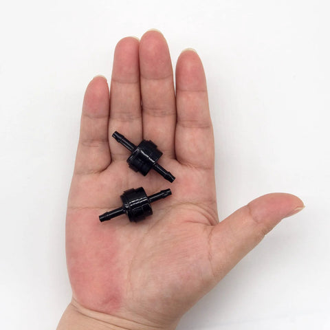 Front view: two black PA66 automotive spring check valves held in a hand