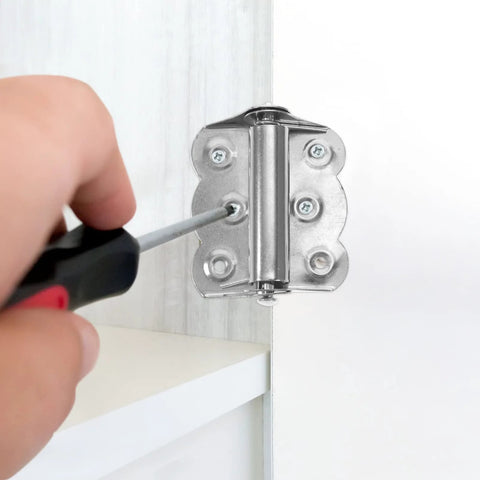 Stainless steel self-closing spring door hinge installed on white door frame; screwdriver near screws.