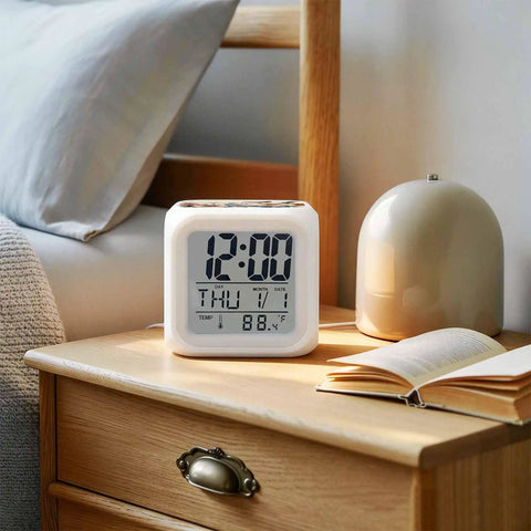 Straight Up Cool Seven Color LED Cube Alarm Clock With Temp And Date Display on bedside table with books.