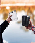 Two people holding Built Tough 304 Stainless Steel Insulated Travel Mugs by a lake, one white and one black.