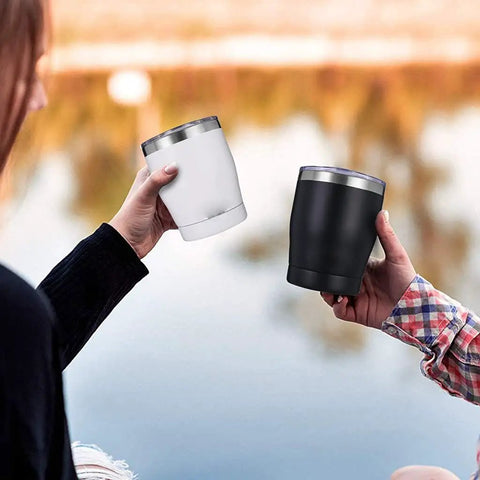 Two people holding Built Tough 304 Stainless Steel Insulated Travel Mugs by a lake, one white and one black.