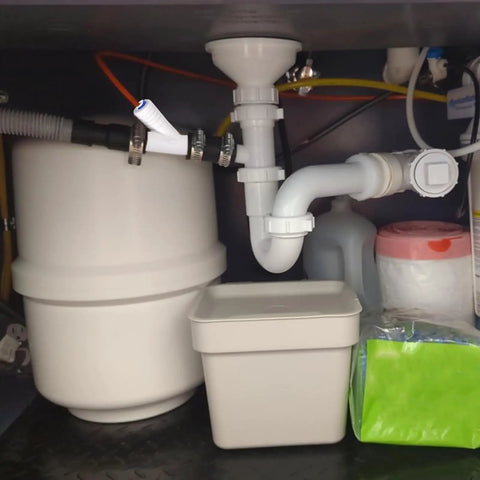 Universal Dishwasher Drain Hose Adapter Kit For RO Water Systems installed under sink with white fittings and hoses.