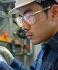 Heavy Duty Z87 Plus Safety Reading Specs With UV400 Side Shields And Impact Resistant Lenses Built Tough For Jobsites And The Daily Grind Featuring One Five X Clearfall Magnification worn by a man inspecting machinery.