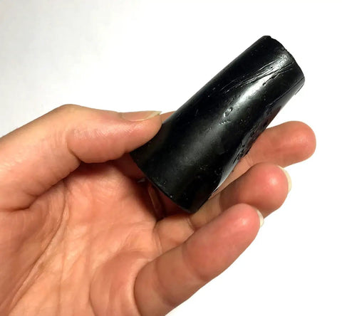 Hand holding a black asphalt plug, part of the Three Quarters Inch Asphalt Plugs 25 Pack For Quick Driveway And Pavement Repair.