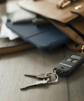 956EV-P2 Keychain Garage Door Remote Control with keys next to a brown leather bag on wooden table