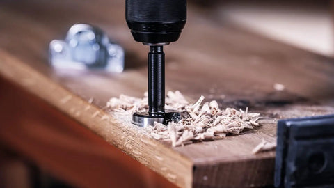 Five Piece Forstner Drill Bit Set With Rugged Three Flat Shank Grip on hardwood creating shavings during blind hole drilling.