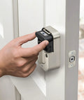 Hand installing Slick Satin Nickel Smart Deadbolt Featuring Bump Proof Touchscreen Keypad on a white door.