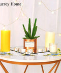 Decorative table setup with yellow candles, faux cactus in pot, and string lights creating a cozy ambiance.
