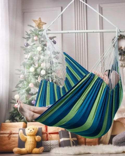 Person relaxing in Ultra Large Hammock Chair Swing With Two Cushions Supports Up To 500 Pounds For Patio Porch Bedroom Backyard Indoor Or Outdoor Use Includes Hanging Hardware Kit inside a room with a Christmas tree.