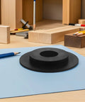 Round black component on light blue surface, part of Wheel Balancer Guard Panel With Drive Belt Cover And Durable Housing Shield.